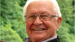 hombre mayor sonriendo y con un paisaje de fondo